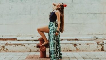 woman in green and black floral dress holding red flower bouquet