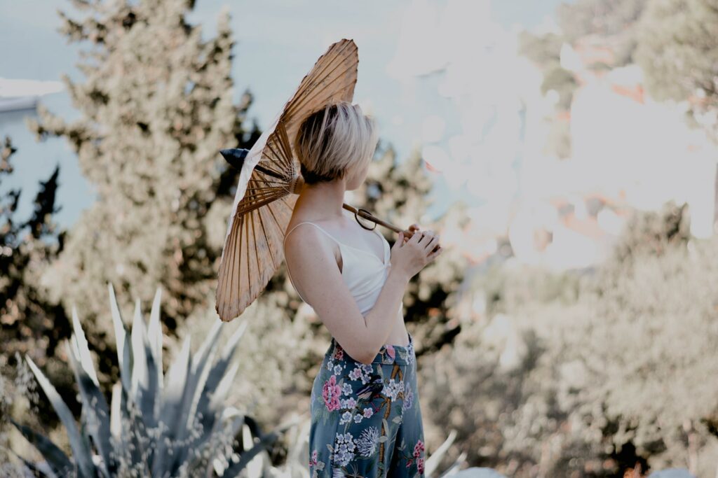 woman in blue and white floral dress holding brown umbrella