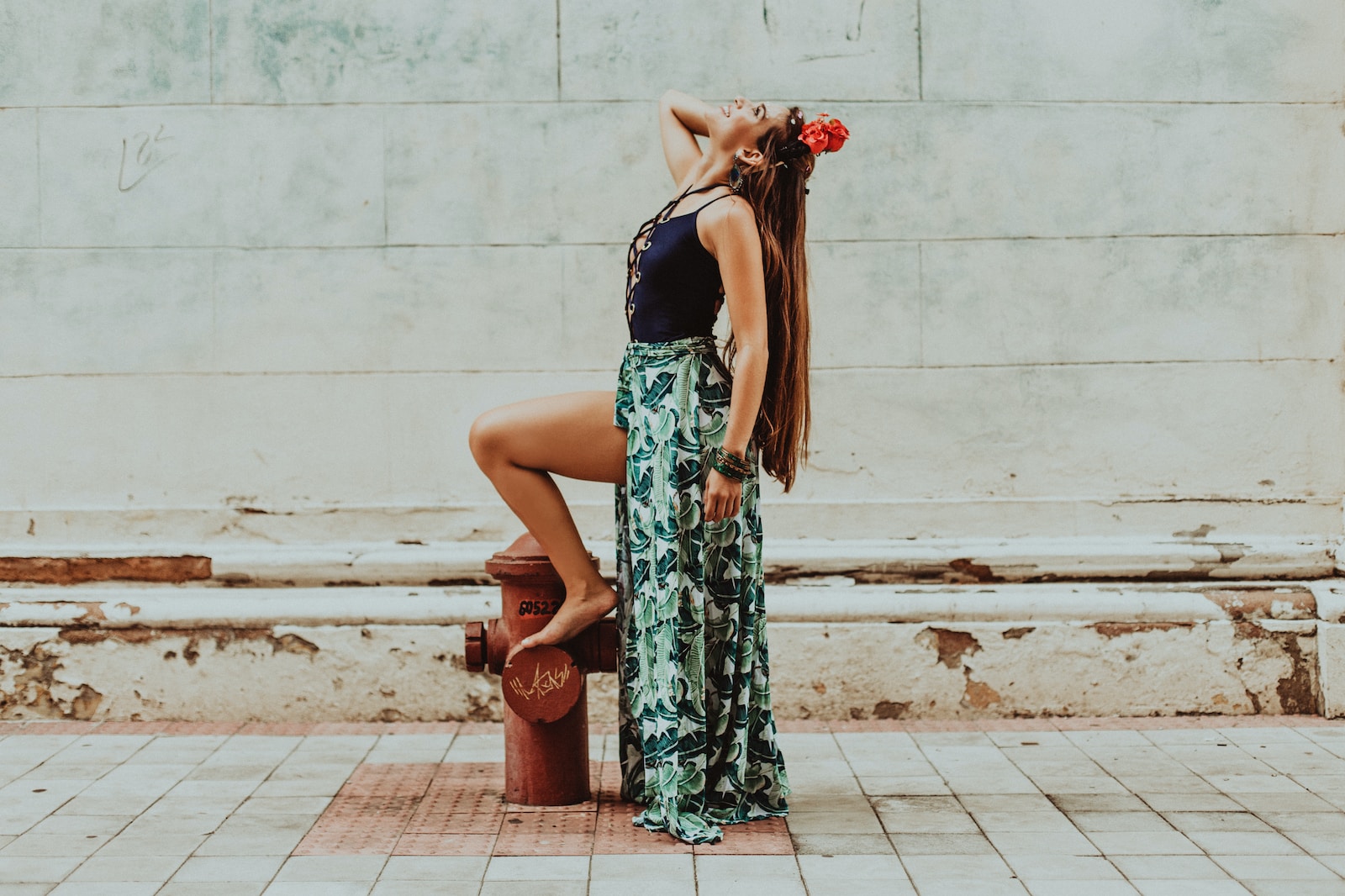 woman in green and black floral dress holding red flower bouquet