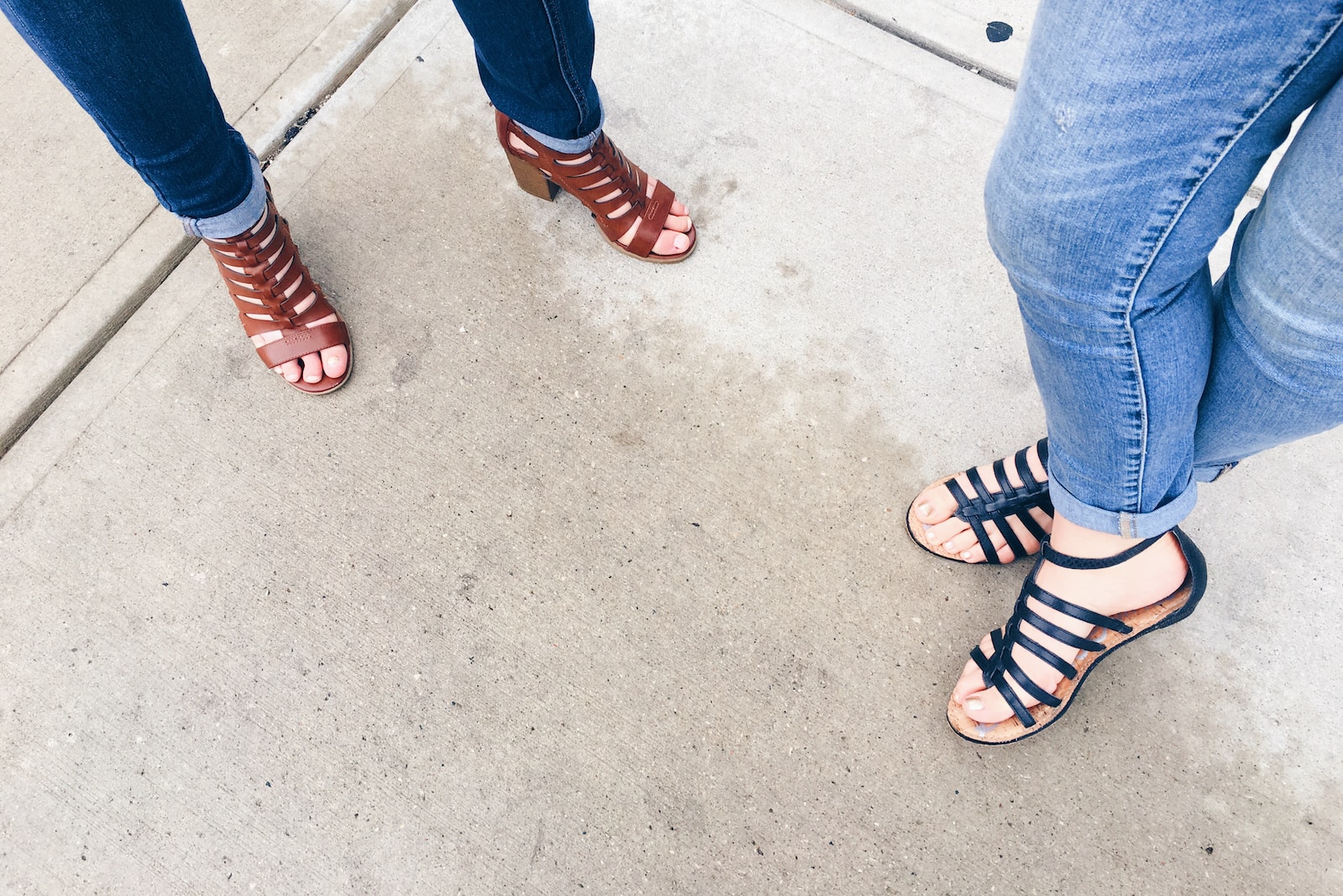 two woman wearing black and brown strappy sandals