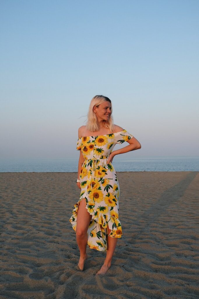 woman in white and yellow floral dress standing on beach during daytime