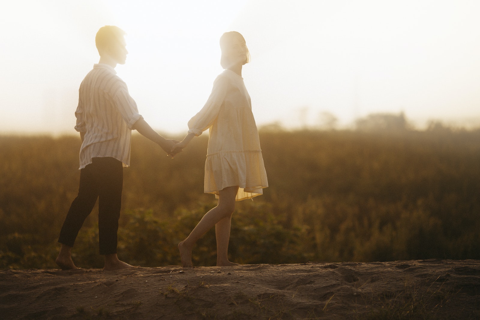 Couple Holding Hands on Sand Field