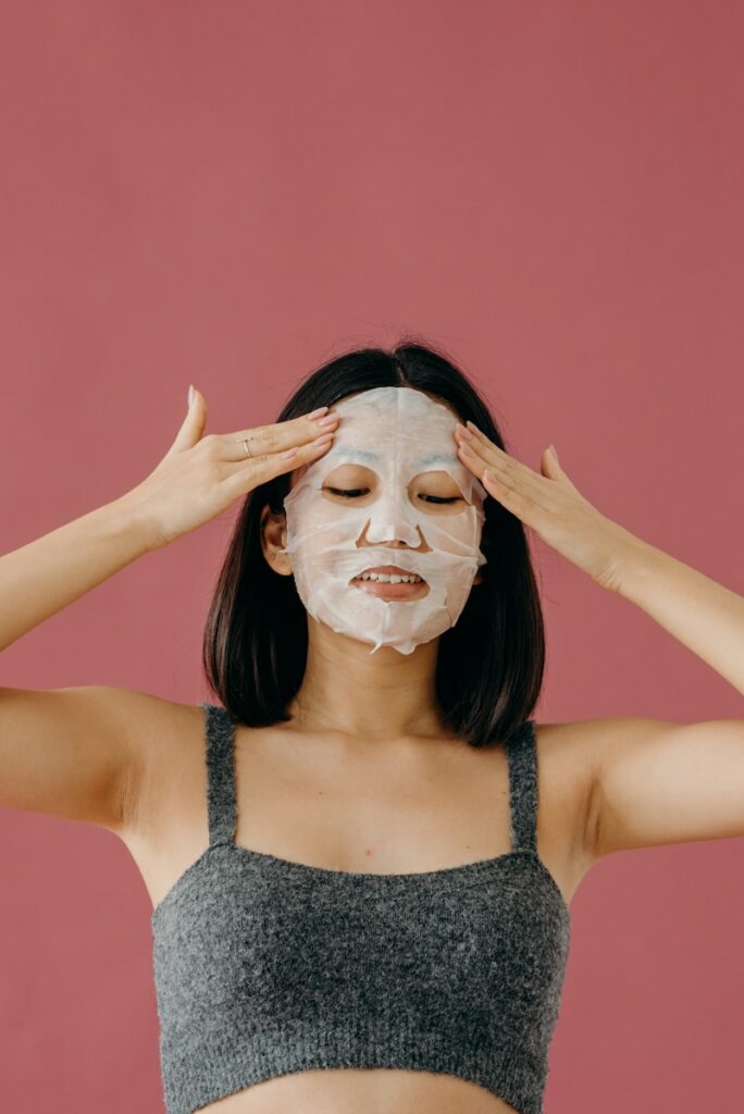 A Woman in Gray Tank Top Touching Her Face with Mask