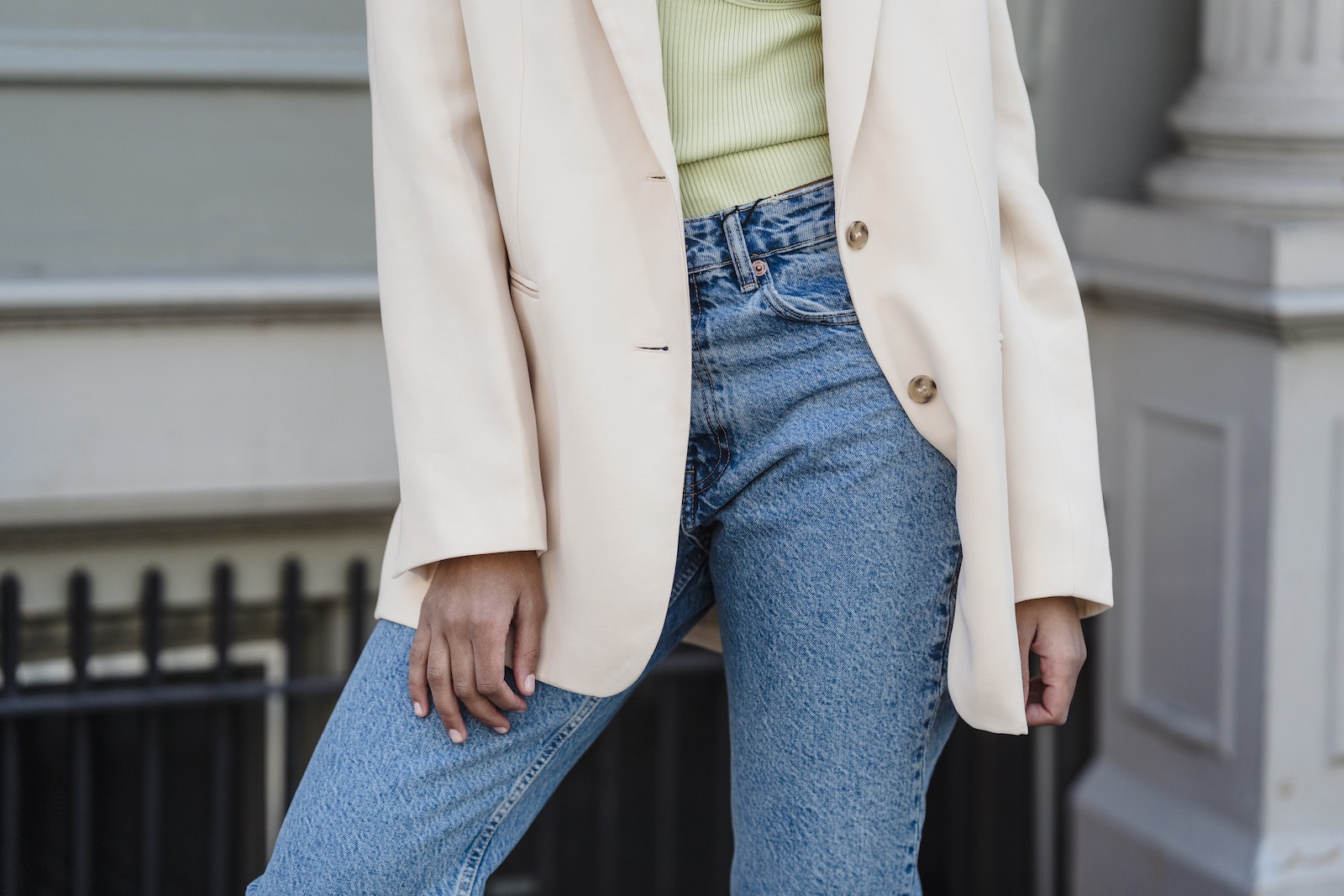 Crop anonymous trendy female in beige jacket and jeans standing in town in daylight