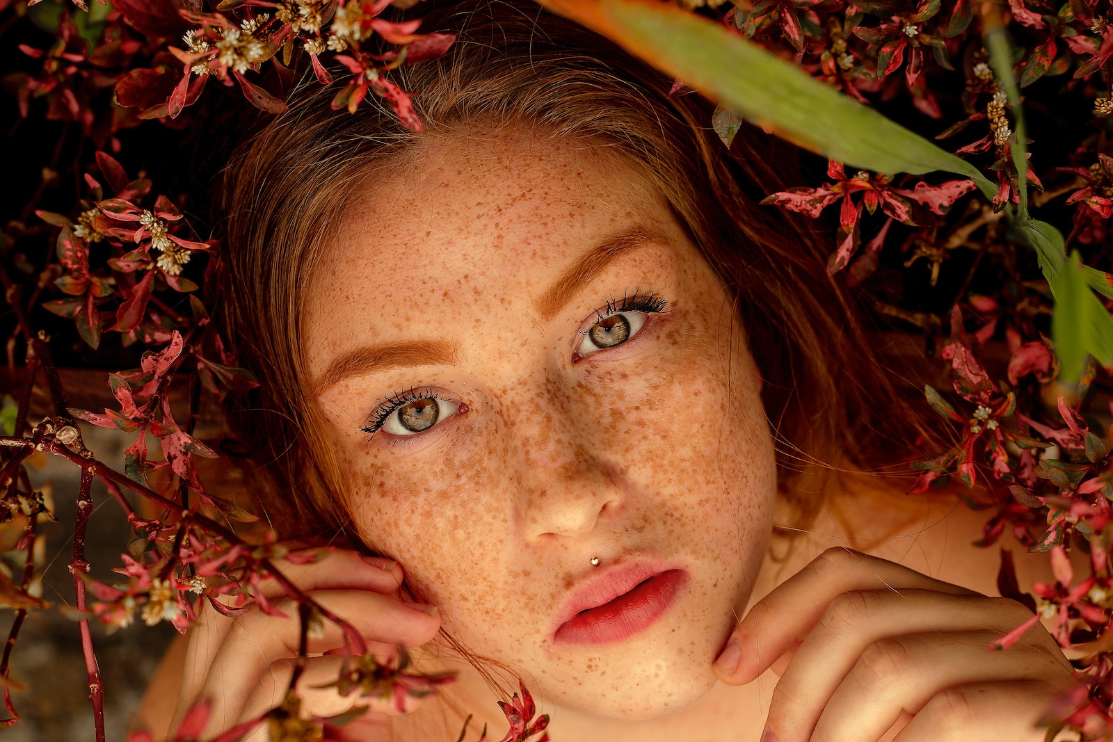 woman with red lipstick lying on brown leaves