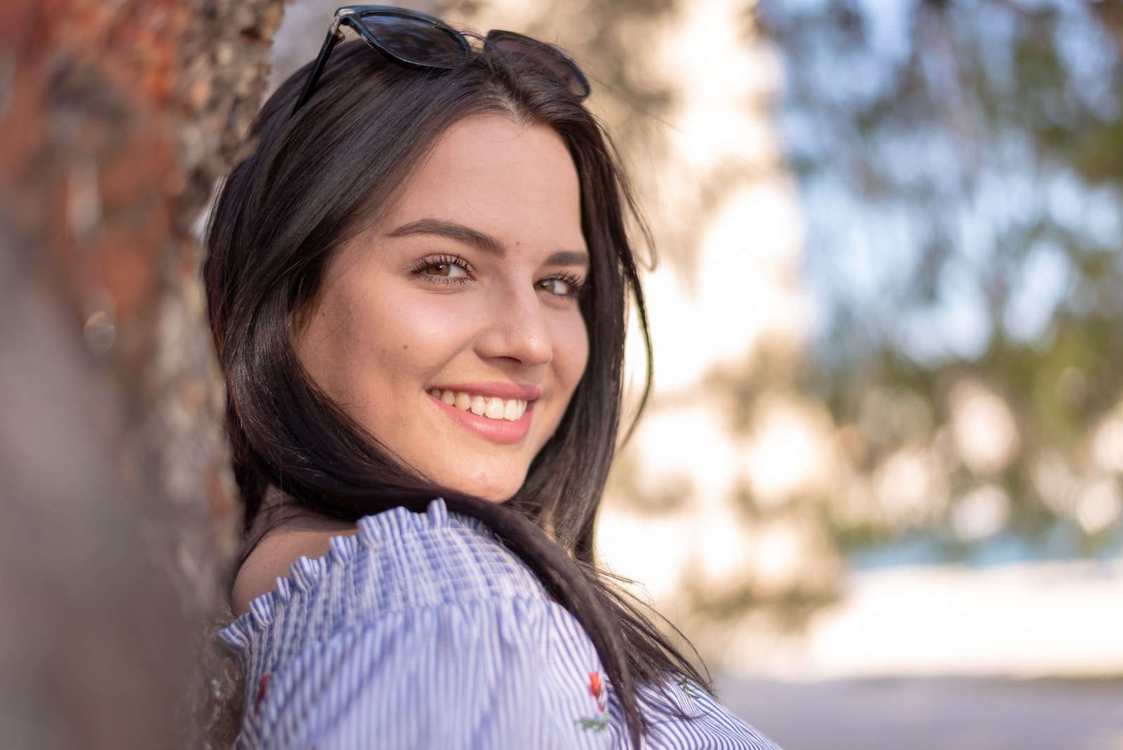 smiling woman in blue and white striped shirt wearing black sunglasses