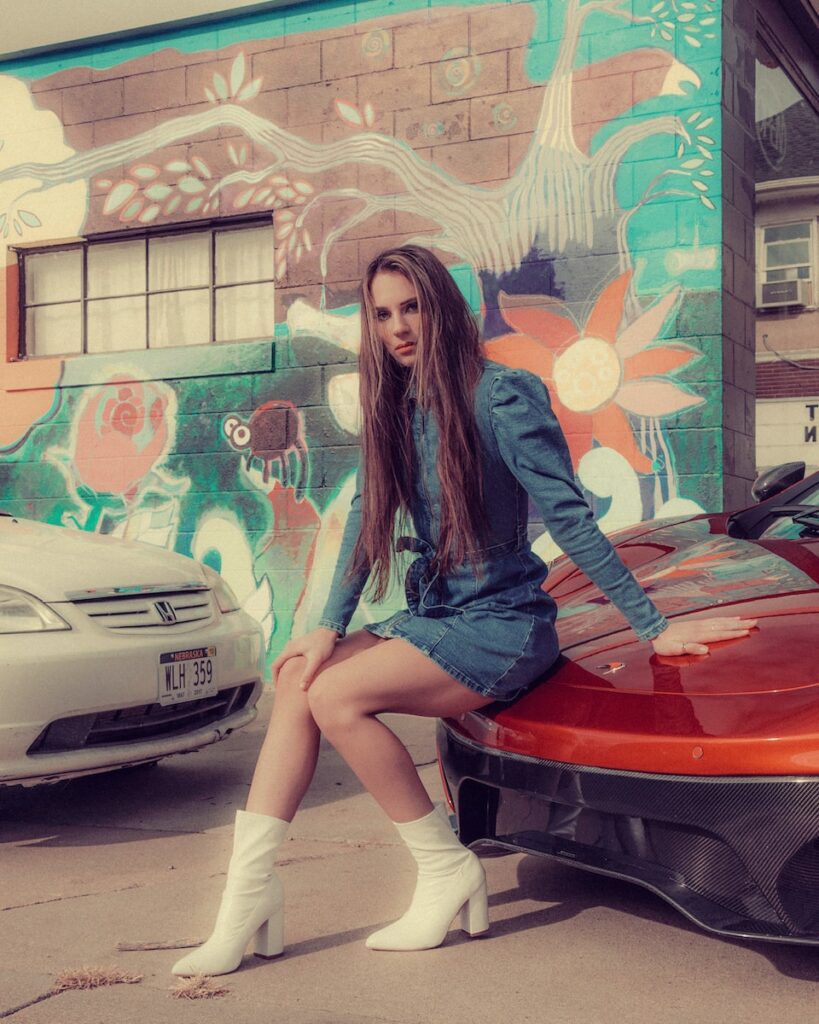 woman in blue long sleeve shirt and blue denim shorts sitting on red car