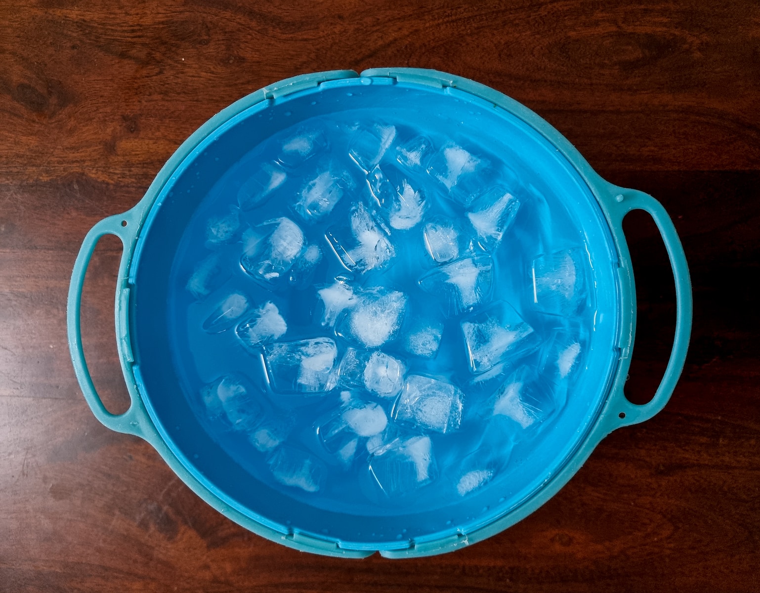 an ice bucket filled with ice cubes on top of a wooden table