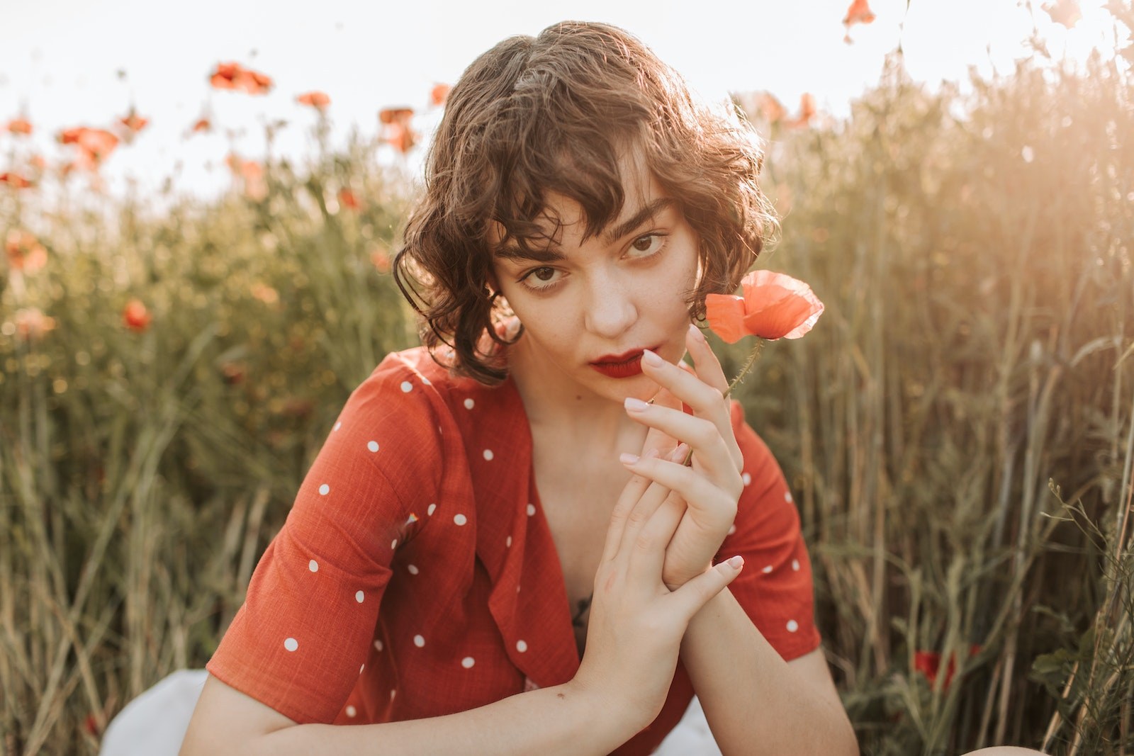 Beautiful Woman with Red Lips Holding a Red Poppy