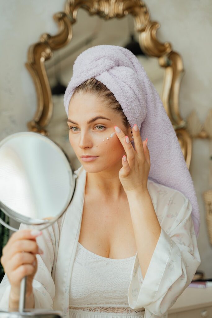 Woman Looking in the Mirror and Applying a Face Cream
