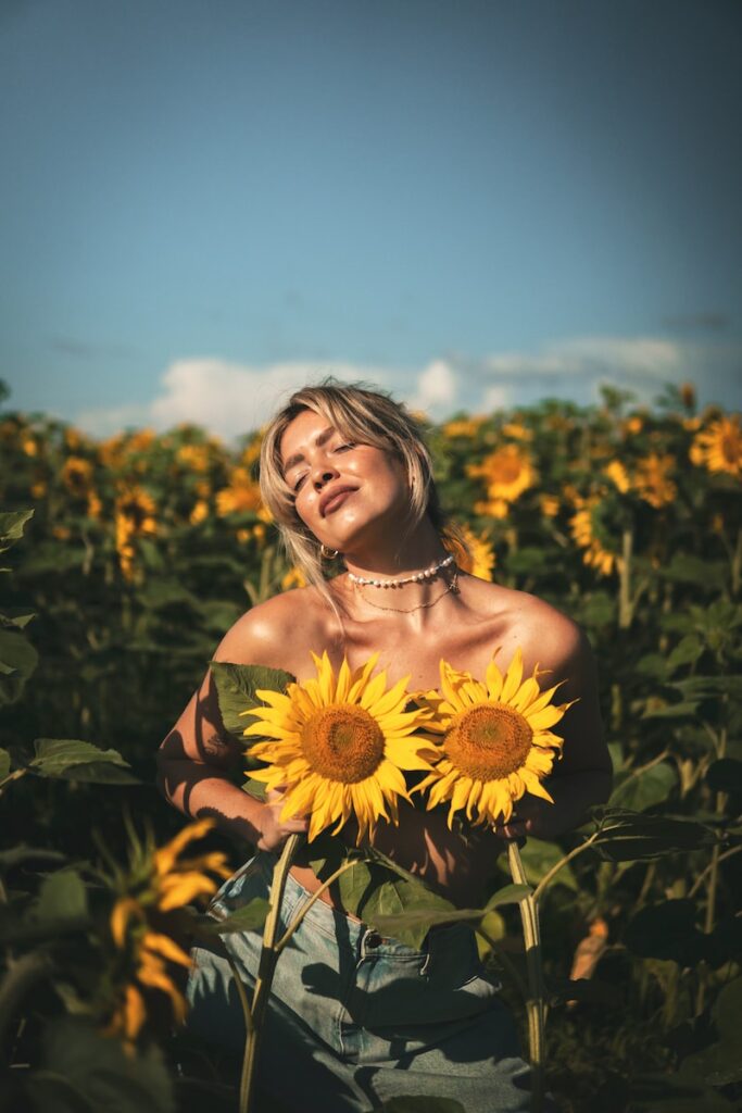 woman in red off shoulder dress holding sunflower
