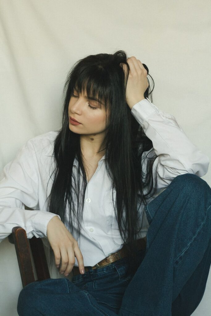 a woman with long black hair sitting on a chair