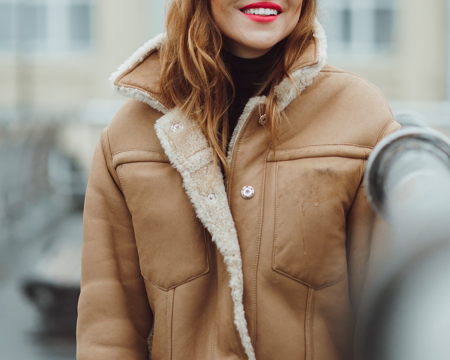 woman in brown coat standing near gray car during daytime