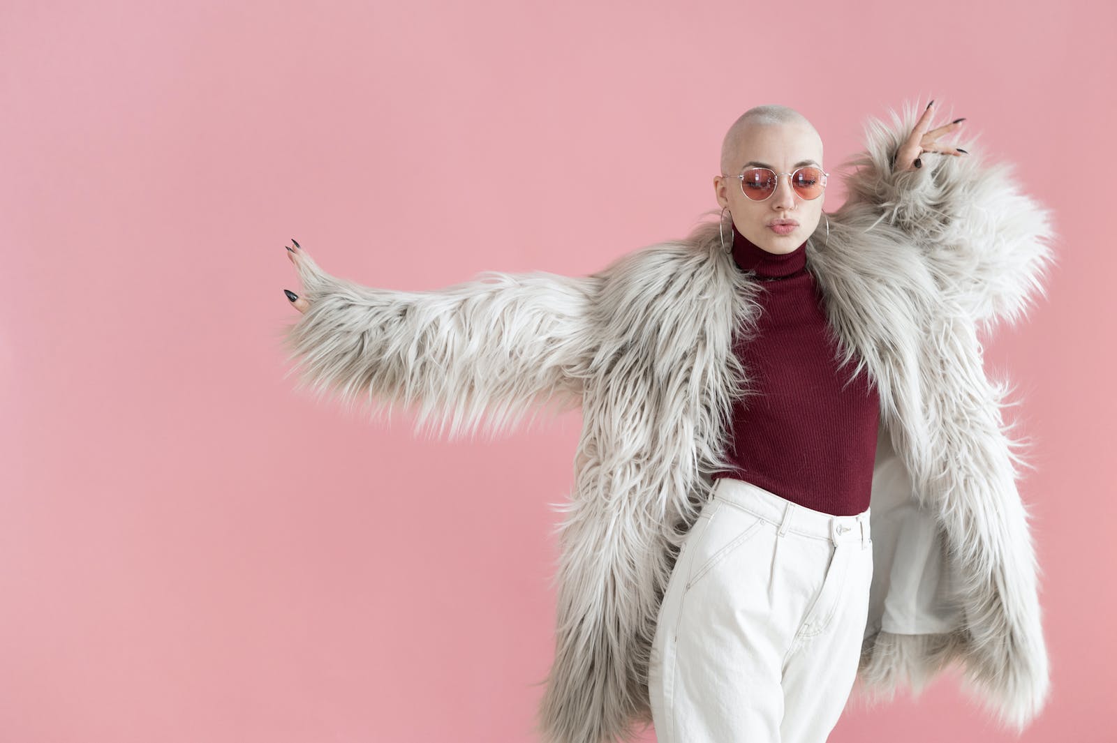 Fashionable woman in fur coat dancing in studio