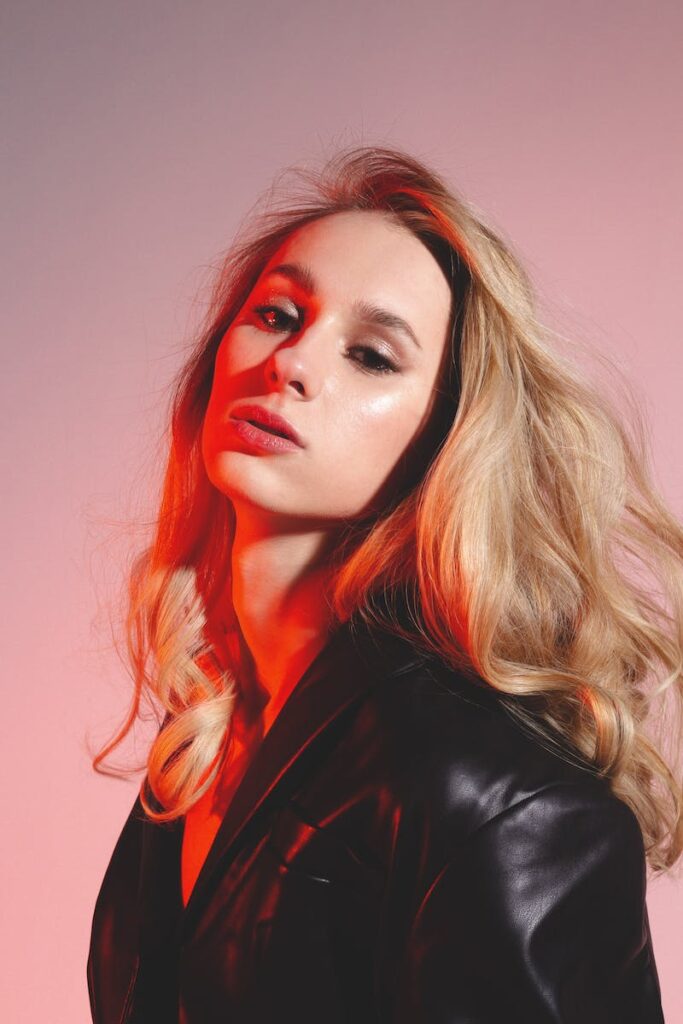 Thoughtful female in trendy outfit in studio with red lights