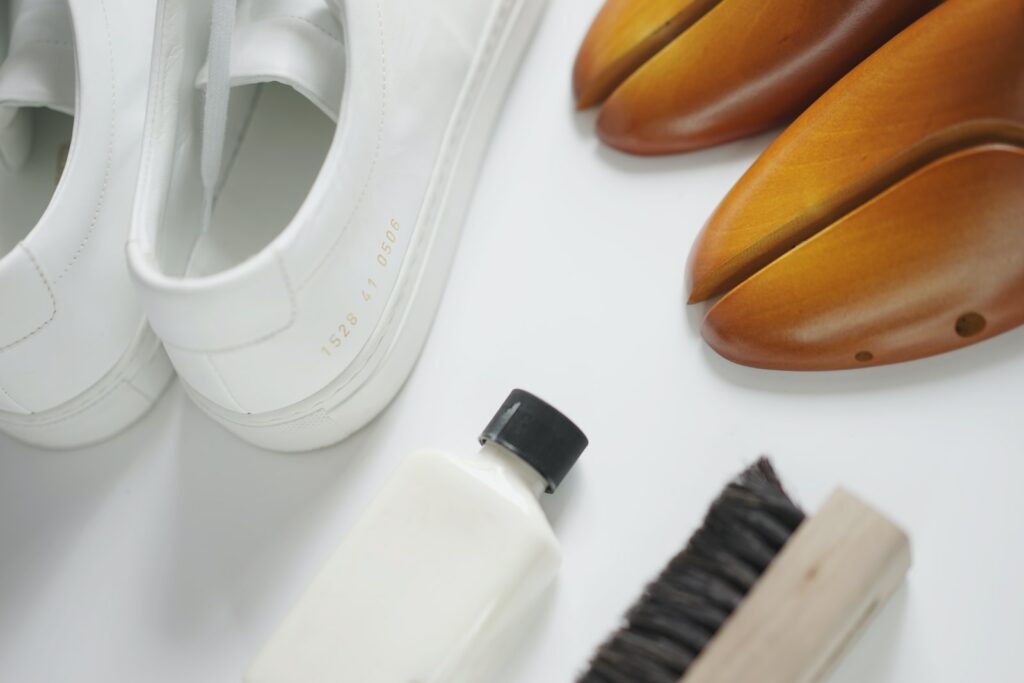 a pair of white shoes next to a white shoe brush