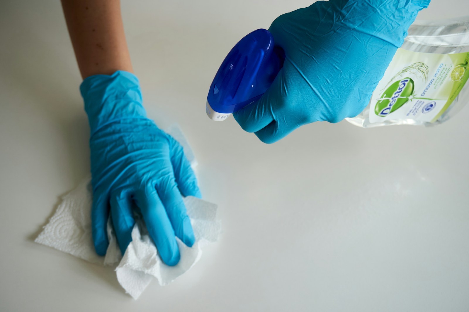 person in blue gloves holding white textile