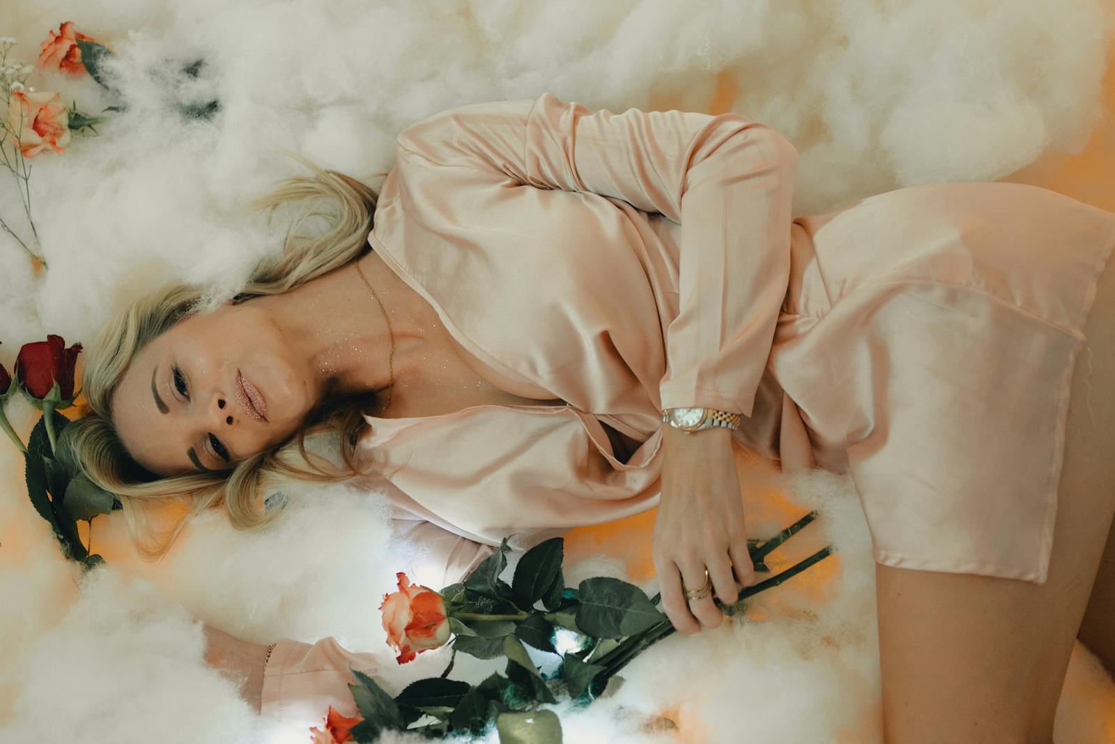 Woman Wearing a Satin Pyjama Lying Down on a Cotton Wool with Roses