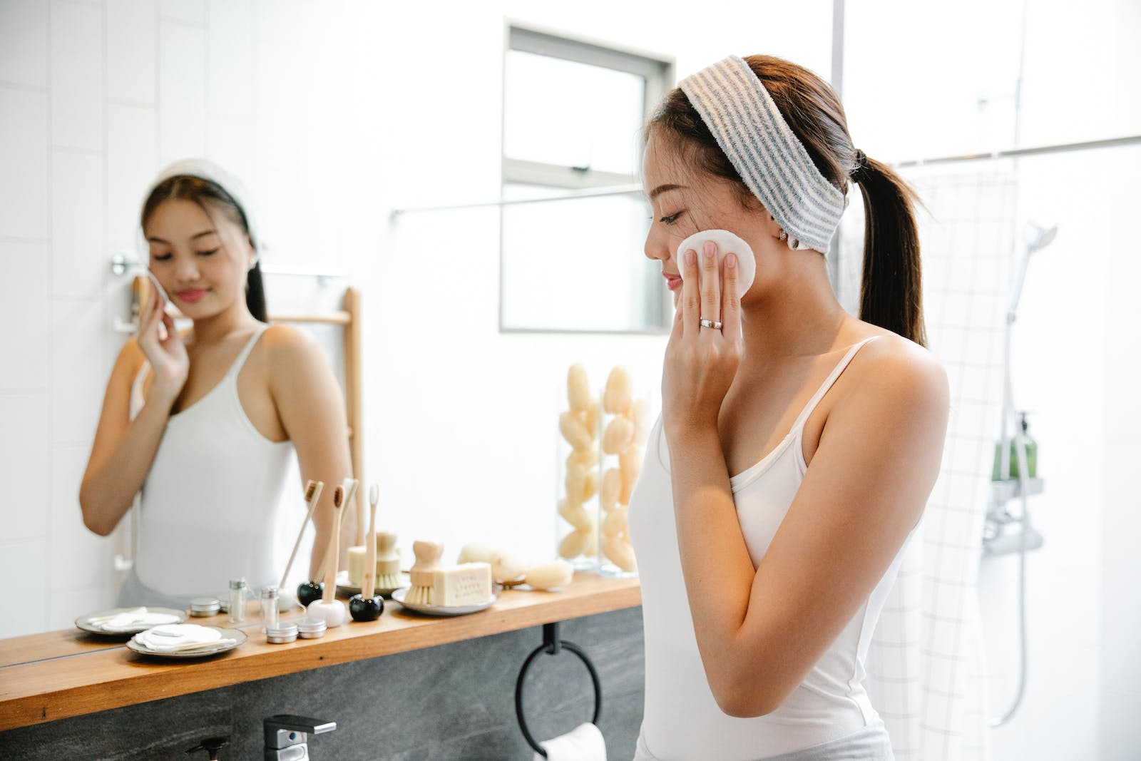 Content Asian woman cleaning face with cotton pad