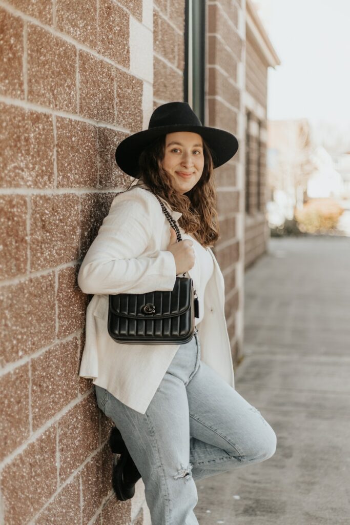 woman in white long sleeve shirt and blue denim jeans wearing black fedora hat sitting on with on with on