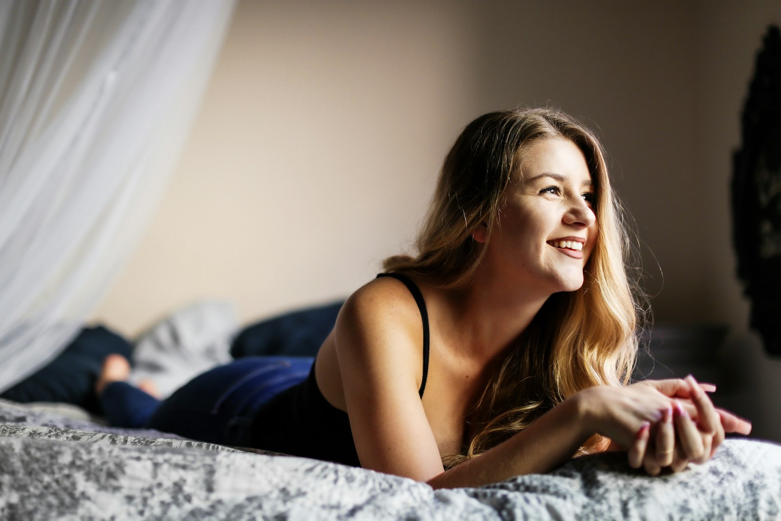 woman in black spaghetti strap top lying on bed