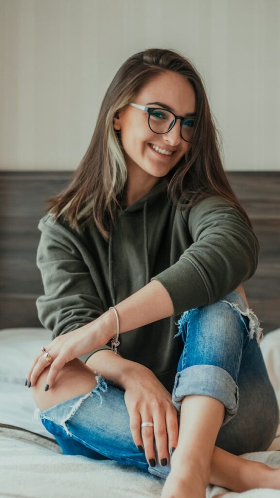 woman in gray sweater and blue denim jeans wearing black framed eyeglasses