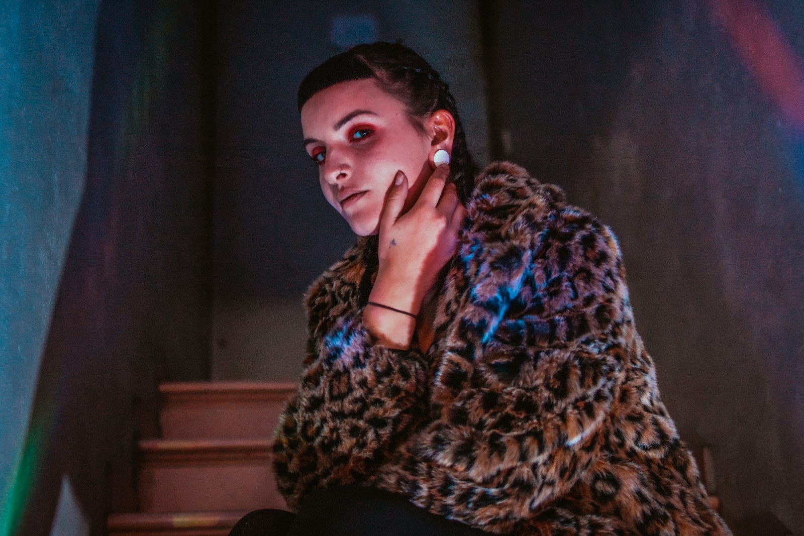 a woman in a leopard coat sitting on a stair case