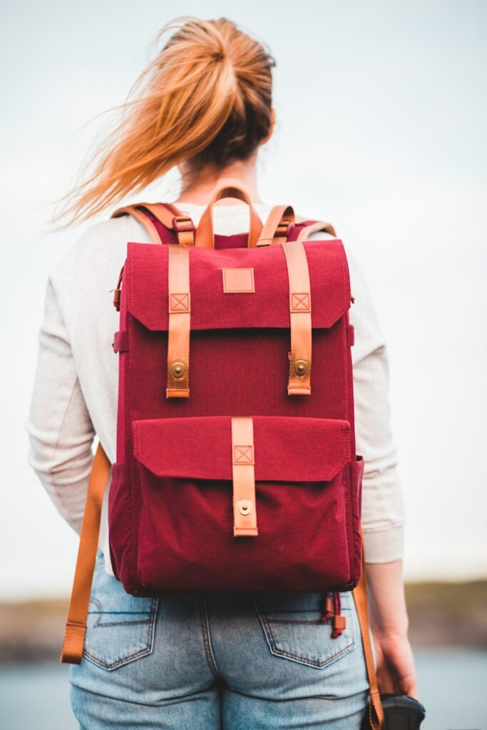 woman in white long sleeve shirt with red and black backpack